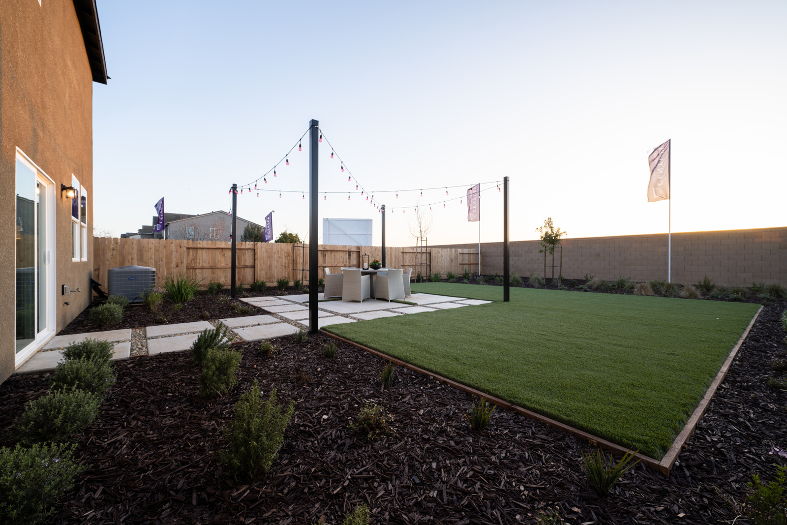 A grassy area with a fence and a building in the background.