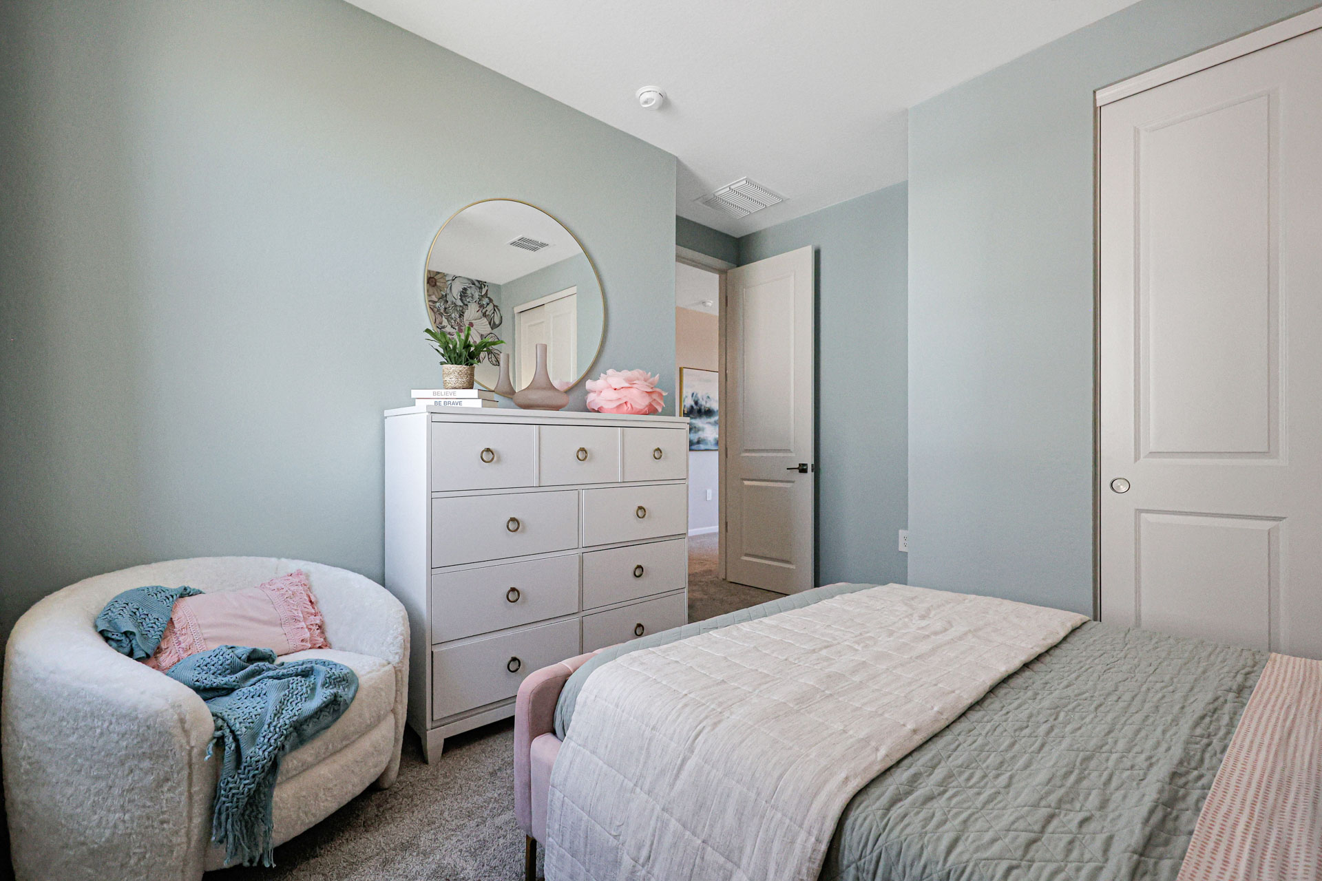 A bedroom with a mirror and dresser.