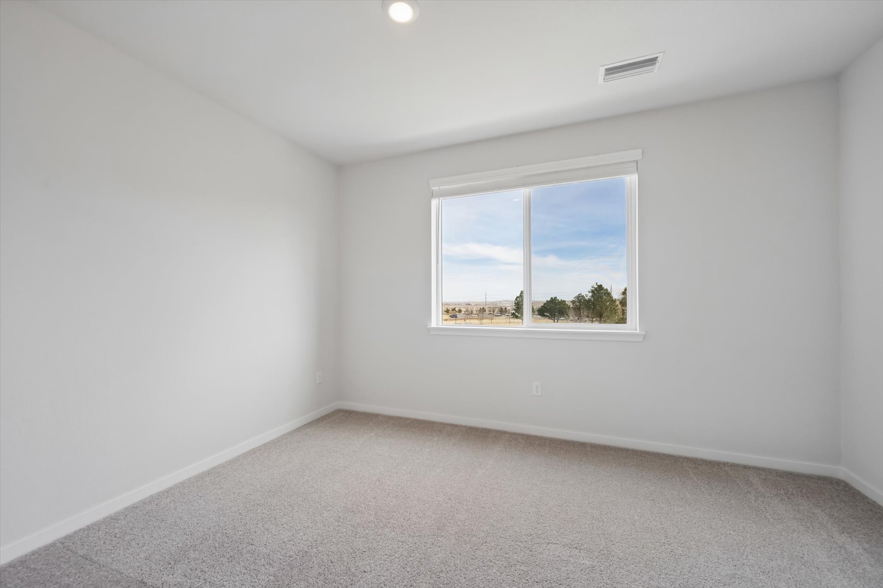 A room with a window and a white wall with a view of the ocean.