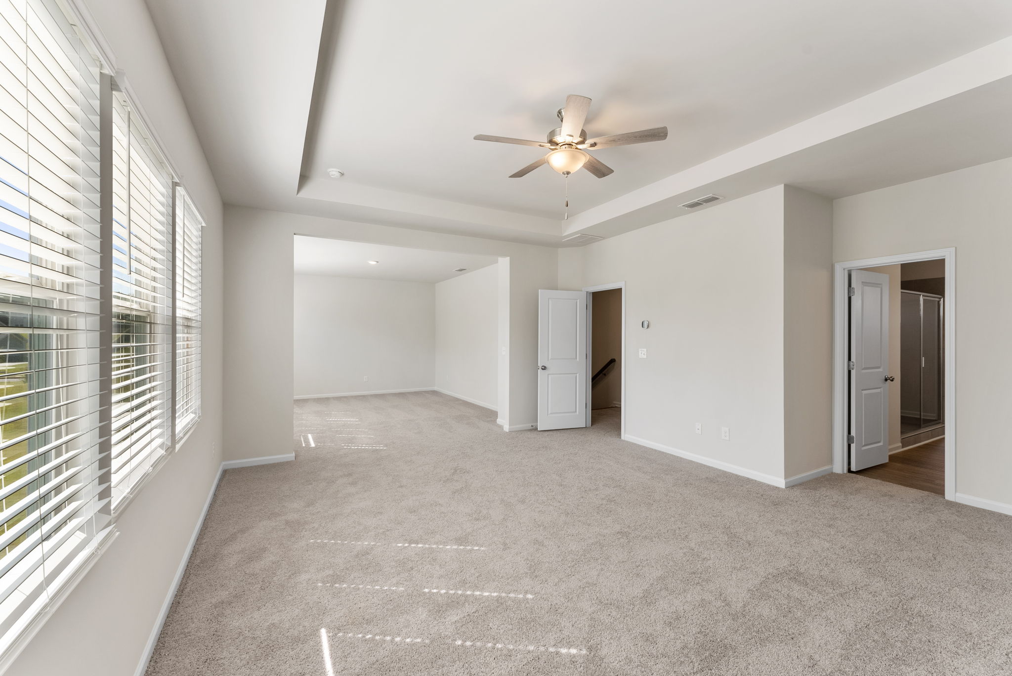 A room with a ceiling fan and a door.