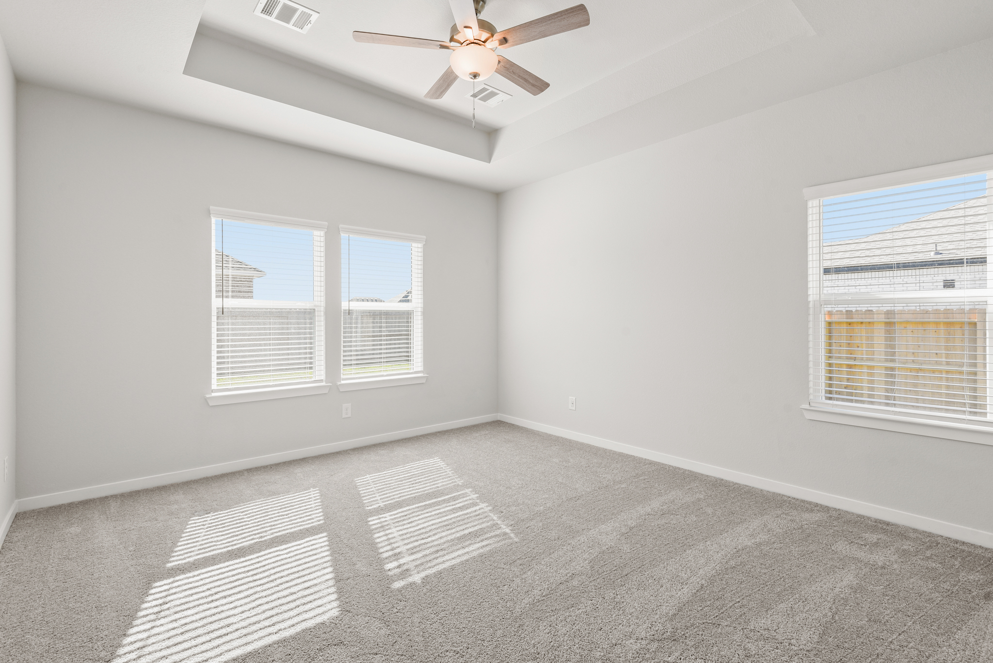 A room with a ceiling fan and windows.