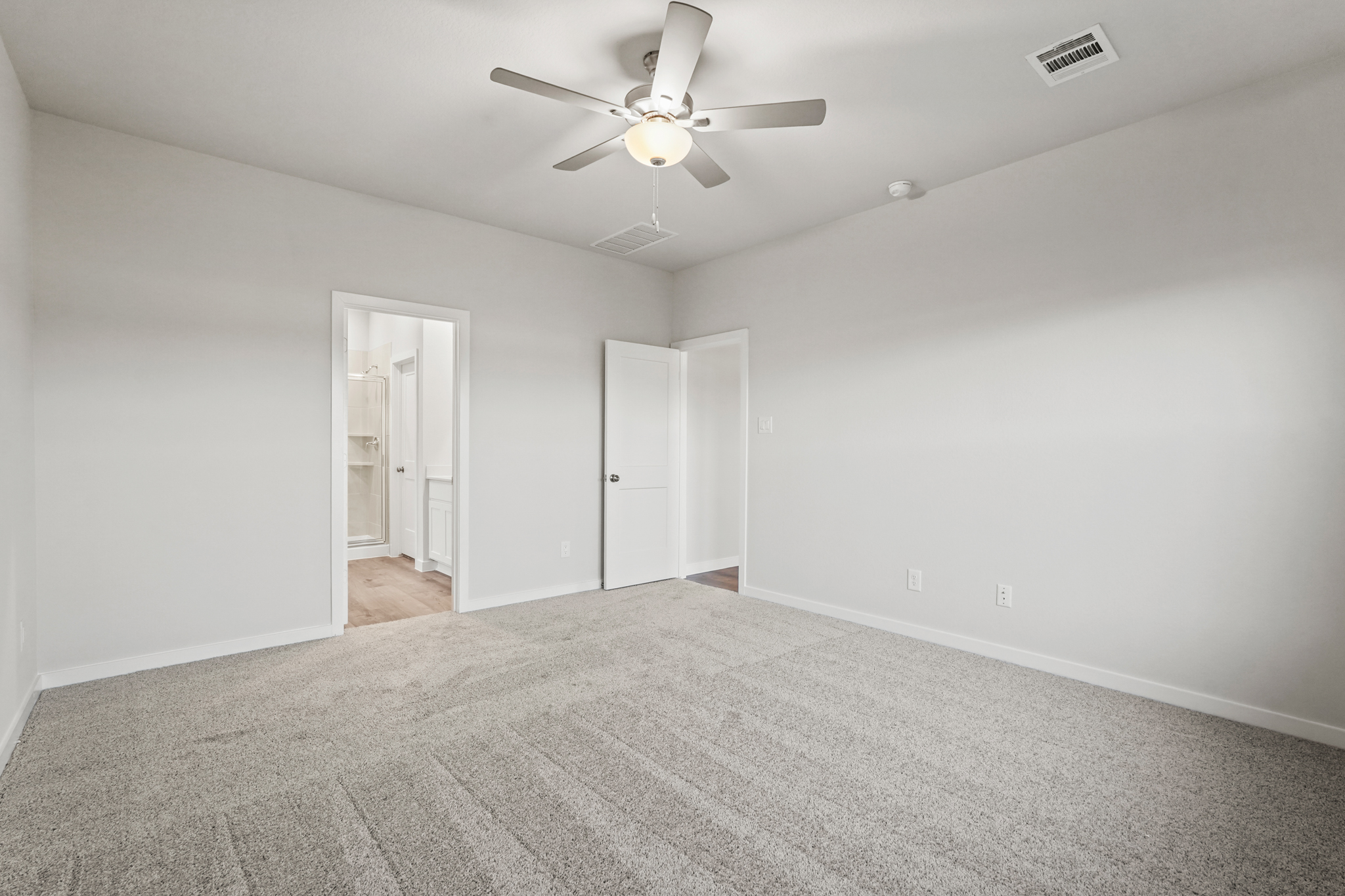 A room with a ceiling fan and a carpet.