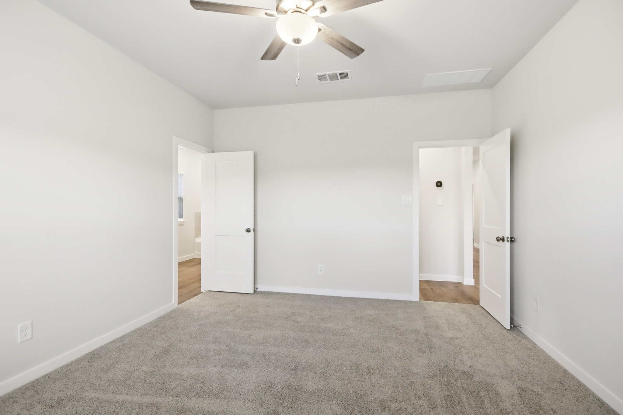 A room with white walls and a ceiling fan.