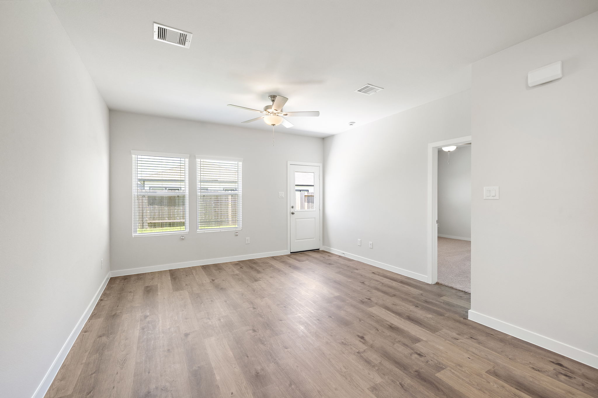 A room with a wood floor and a ceiling fan.