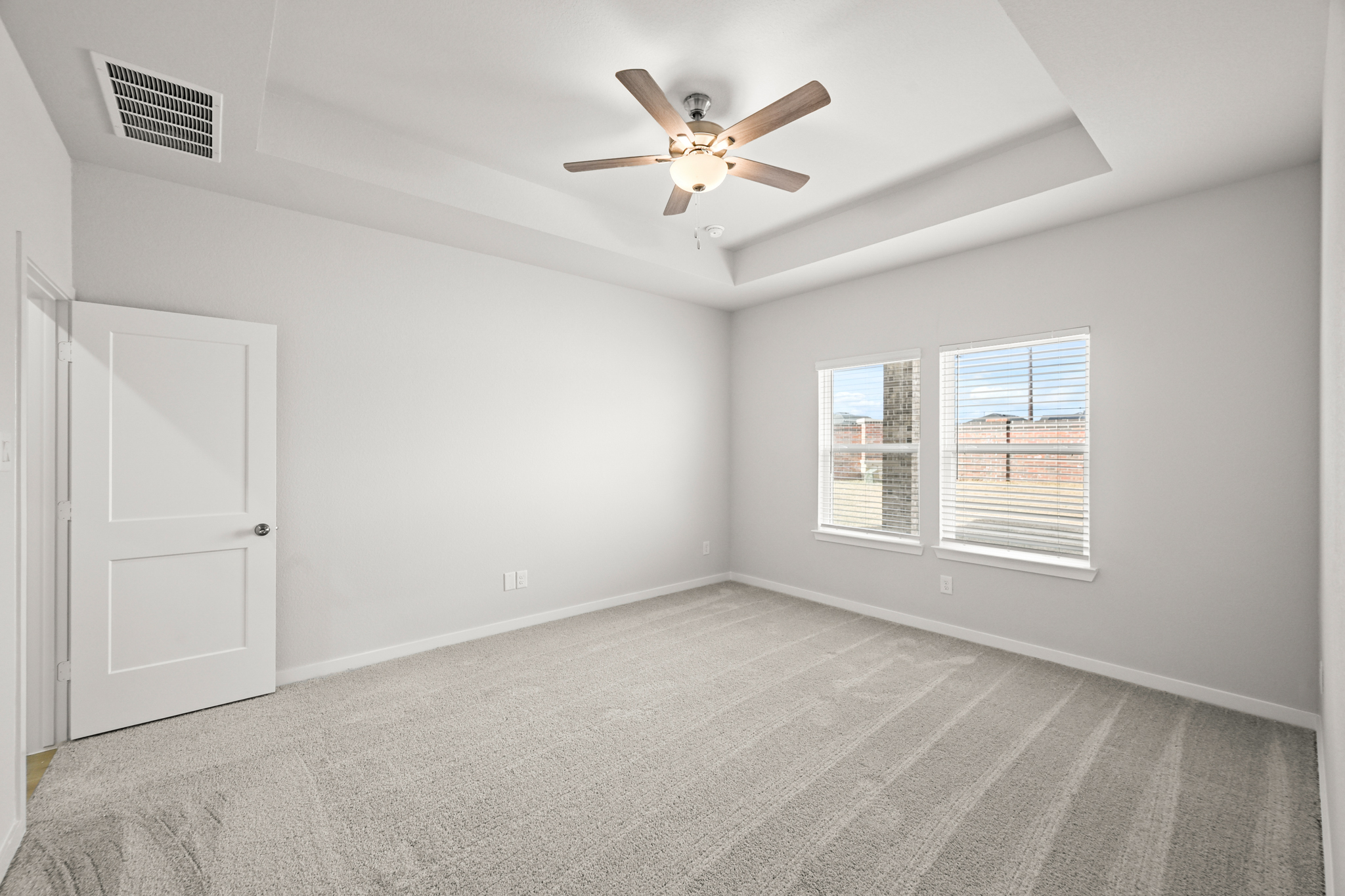 A room with a ceiling fan and a door.