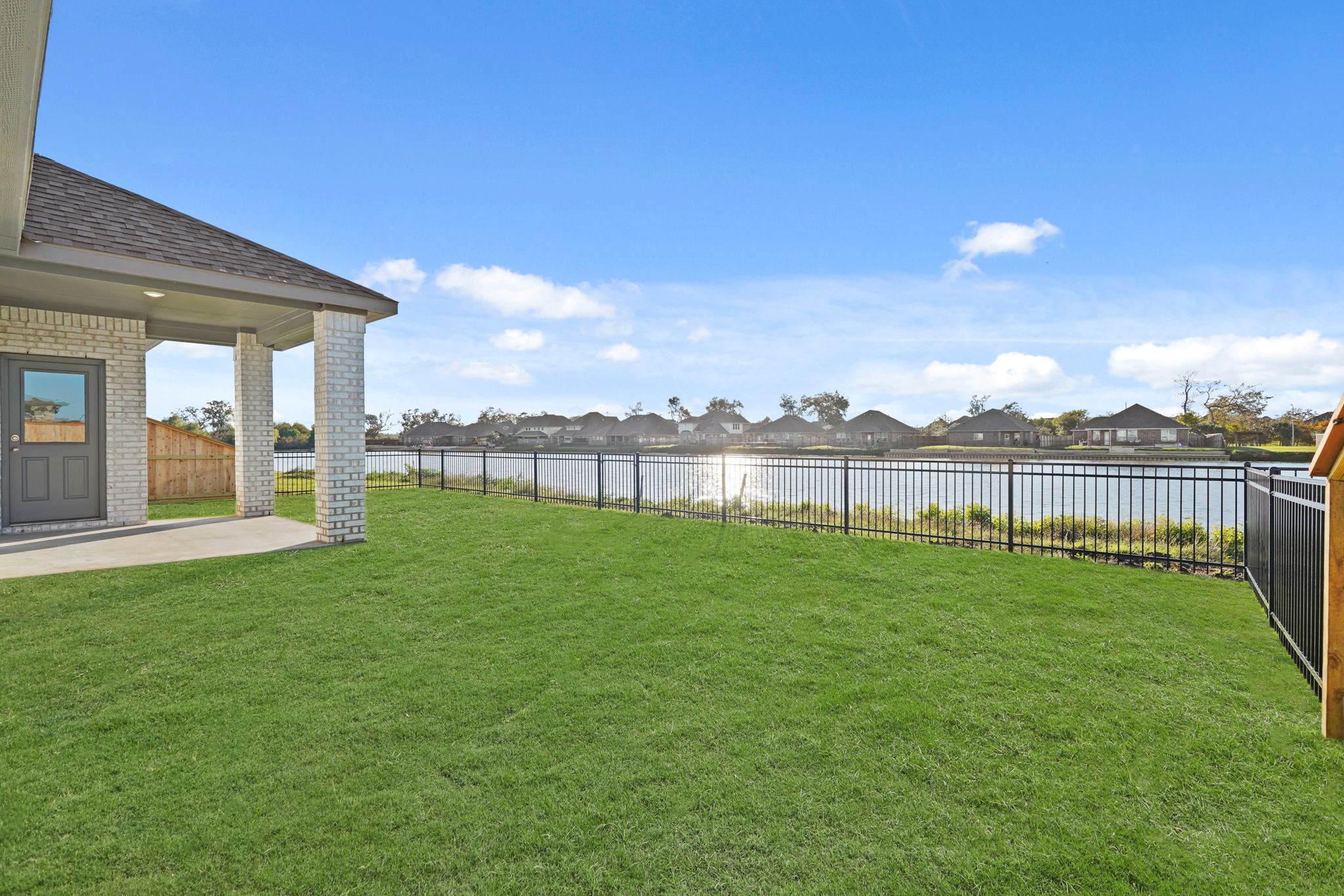 A fenced in yard with a house and a building in the background.