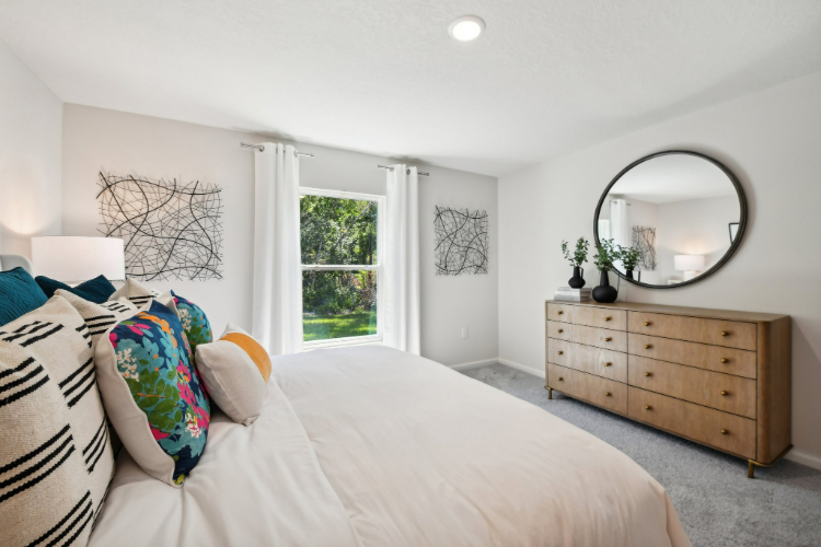 A bedroom with a bed and a mirror.