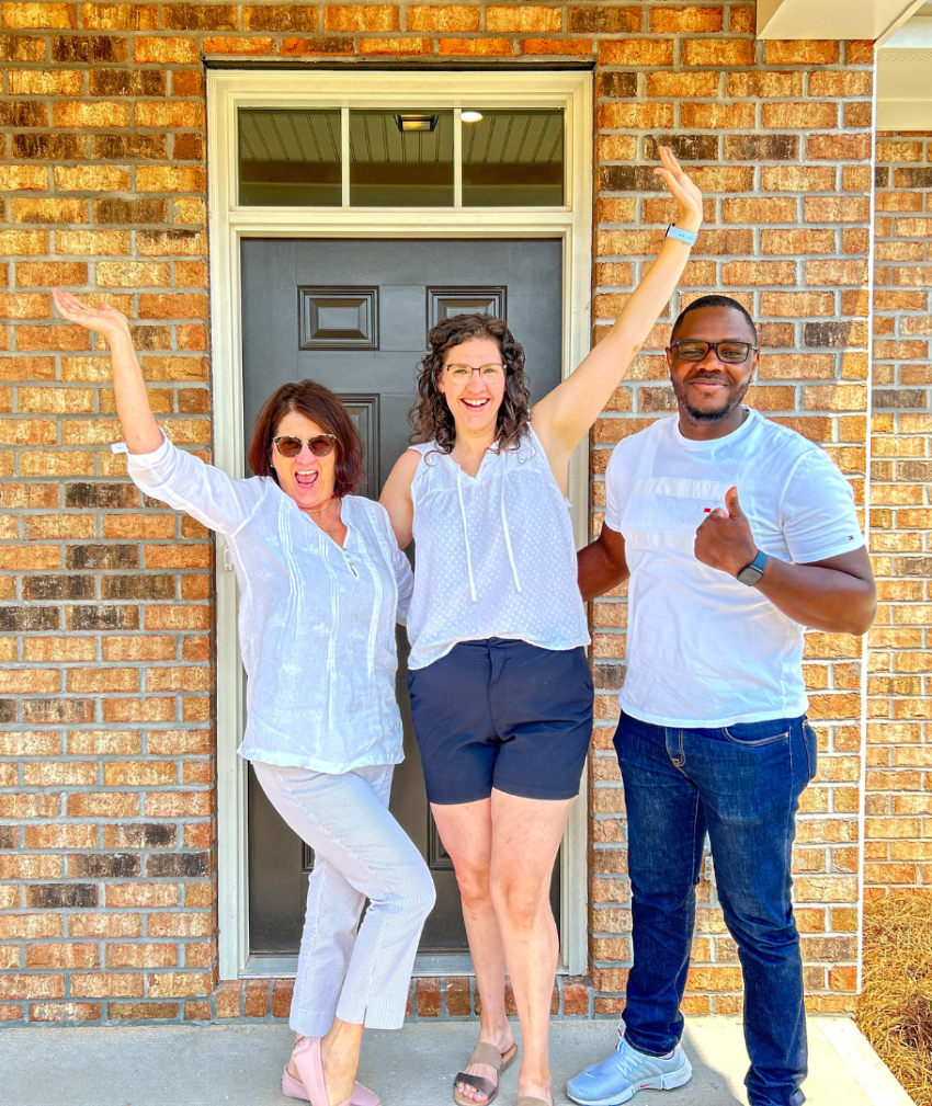 A group of people posing for a photo in front of a brick building.
